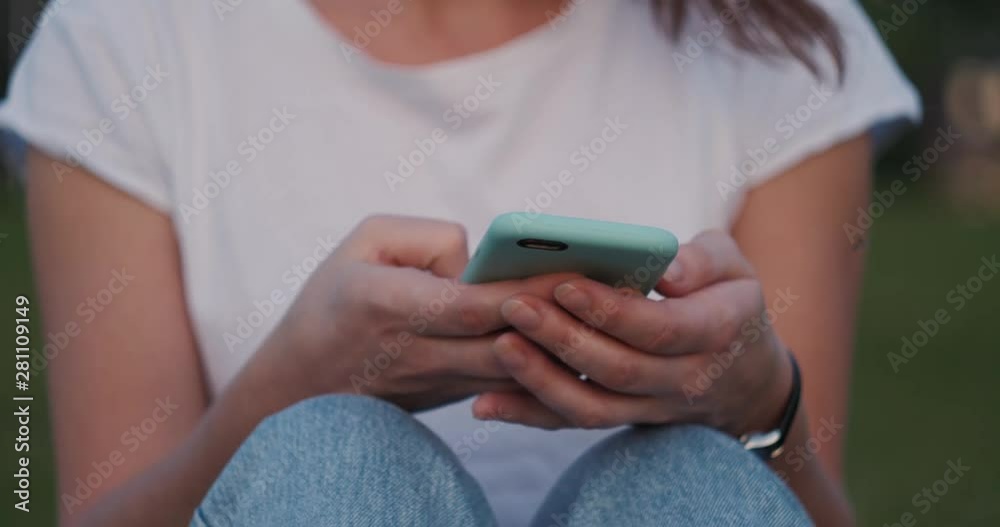 Beautiful young woman typing on phone outdoors. Plants in the background in park Concept of modern technology and internet. Beautiful young woman typing on phone outdoors. Plants in the background in park Concept of modern technology and internet.