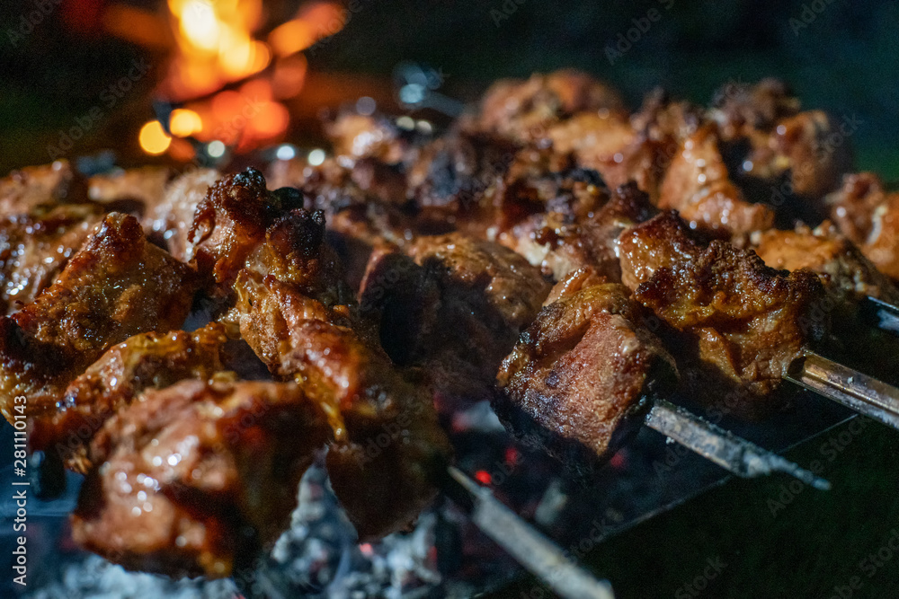 Close-up of grilled kebab on skewers on the grill at night. Well-done kebab close-up