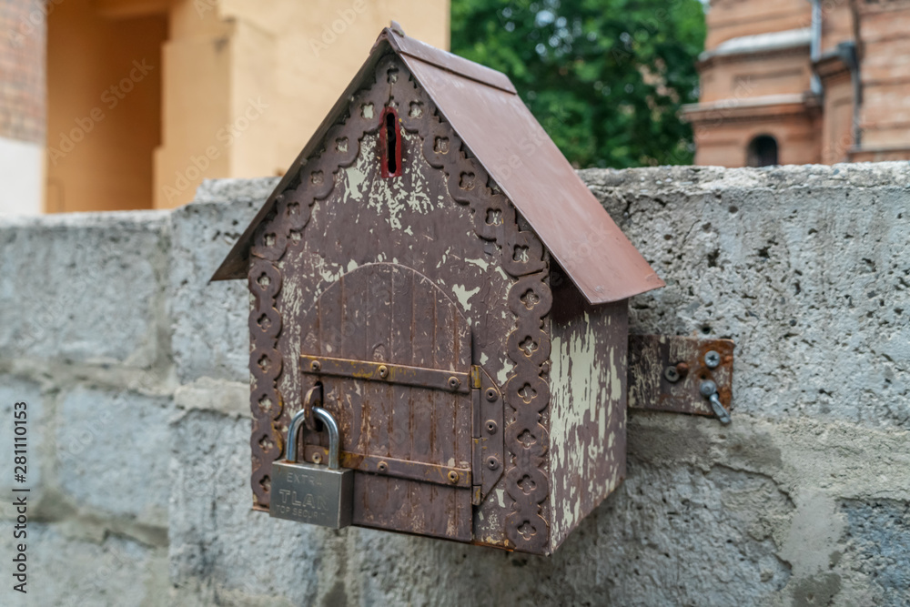 Toy house, a place for donations, attached to a stone fence close-up