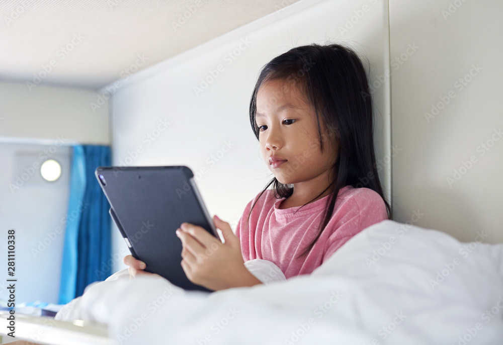 Asian little girl on the train, looking at tablet Asian little girl on the train, looking at tablet