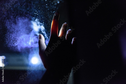 Close up of woman's hand with light and dust in dark room