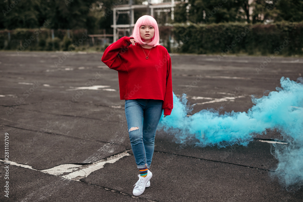 Fototapeta premium Female hipster with blue smoke bomb on street
