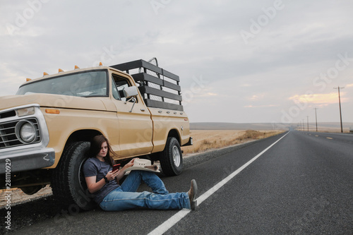 cowgirl leaning against pickup park along road