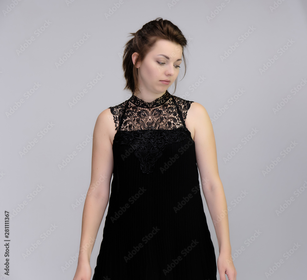 A portrait above the knee of a pretty beautiful fashionable adult brunette girl in a black dress on a white background. Standing right in front of the camera, showing different poses and emotions. A portrait above the knee of a pretty beautiful fashionable adult brunette girl in a black dress on a white background. Standing right in front of the camera, showing different poses and emotions.