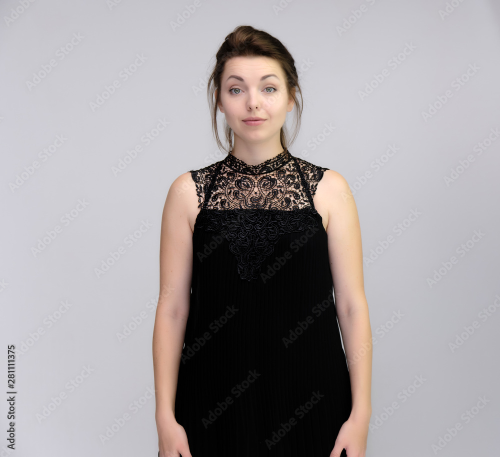A portrait above the knee of a pretty beautiful fashionable adult brunette girl in a black dress on a white background. Standing right in front of the camera, showing different poses and emotions. A portrait above the knee of a pretty beautiful fashionable adult brunette girl in a black dress on a white background. Standing right in front of the camera, showing different poses and emotions.