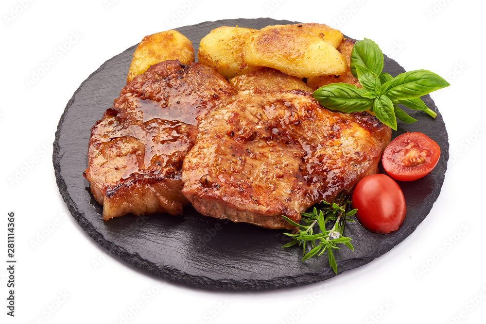 Baked juicy pork steak with fried potatoes on a stone plate, isolated on white background