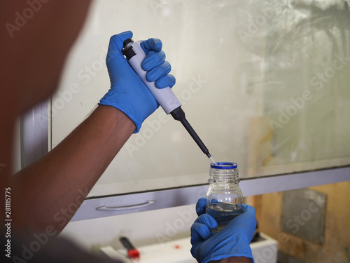 men's hands scientists are using aquatic release micropipette into the test tube. The process of research and development in laboratory science