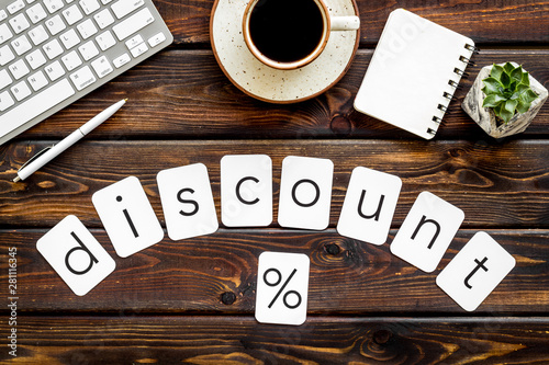 Sale in shop office with discount word and percent symbol, keyboard, notebook on wooden background top view