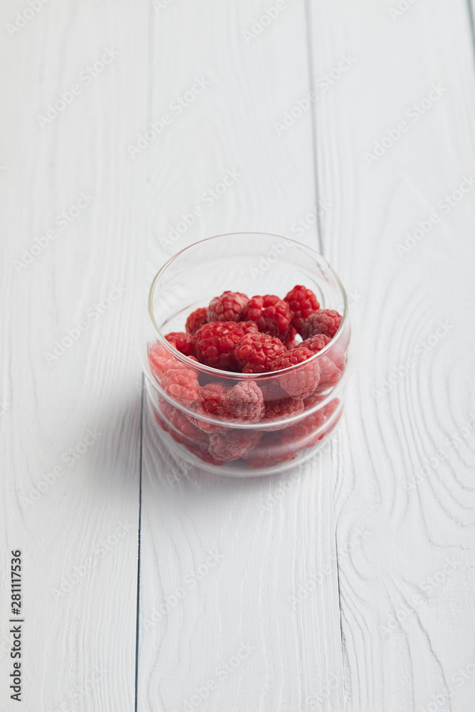 glass with fresh raspberries on white wooden table glass with fresh raspberries on white wooden table