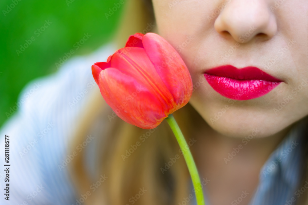 Young pretty caucasian woman's lips with red lipstick and red tulip close up view, dating, wedding day