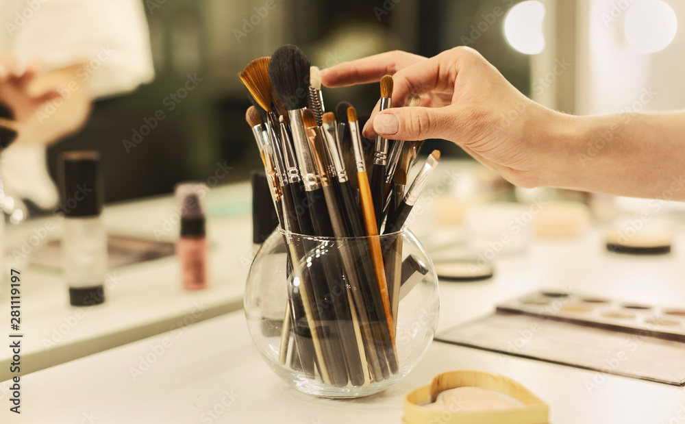 Makeup Artist's Hand Taking Brush From Vase With Professional Tools