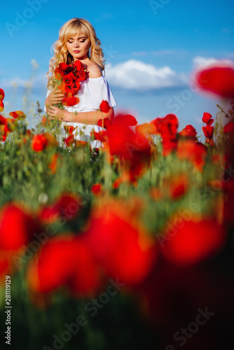 cheerful girl with curly blond hair in a huge poppy field alone,