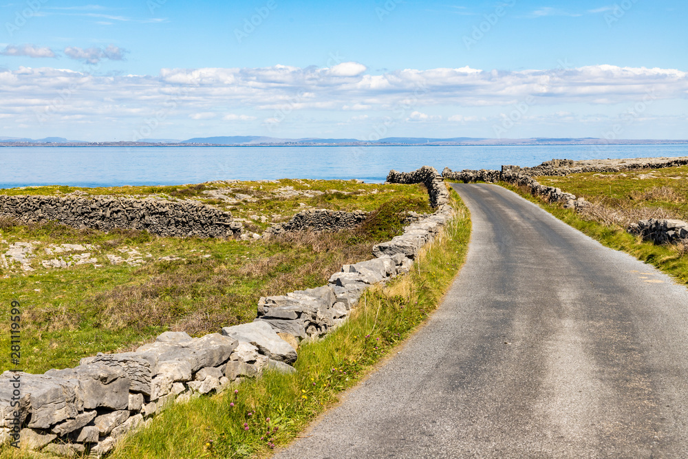 Farm road with rock walls and Galway bay in background in Inishmore Farm road with rock walls and Galway bay in background in Inishmore