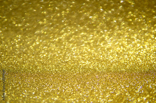Abstract blurred background of golden glitter light partly in focus.