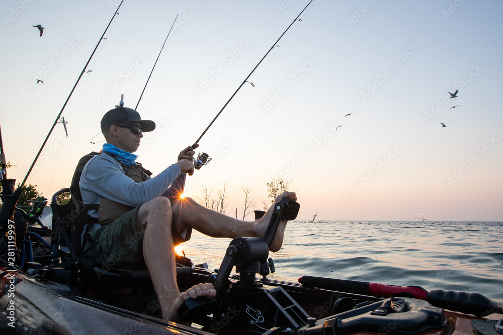 Obraz premium Young Man Kayak Fishing at Sunrise in Canada