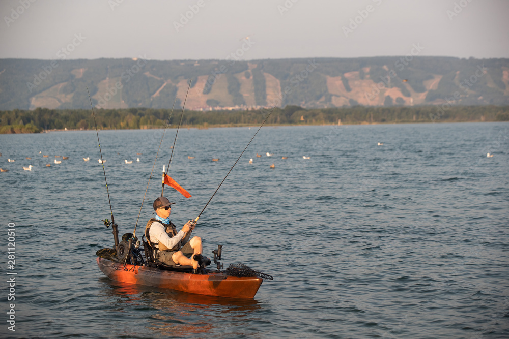 Obraz premium Young Man Kayak Fishing at Sunrise in Canada