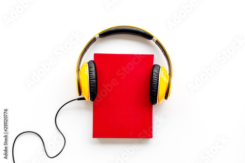Listening audio books with headphones in library on wooden background top view