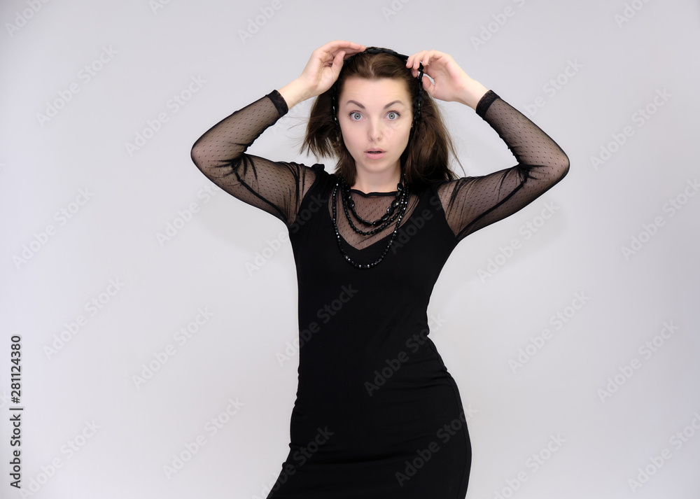 Portrait on white background of a pretty slim beautiful fashionable adult girl with beautiful brunette hair in a black dress. Standing talking demonstrating different poses and emotions Portrait on white background of a pretty slim beautiful fashionable adult girl with beautiful brunette hair in a black dress. Standing talking demonstrating different poses and emotions