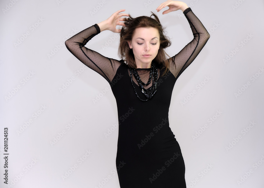 Portrait on white background of a pretty slim beautiful fashionable adult girl with beautiful brunette hair in a black dress. Standing talking demonstrating different poses and emotions Portrait on white background of a pretty slim beautiful fashionable adult girl with beautiful brunette hair in a black dress. Standing talking demonstrating different poses and emotions