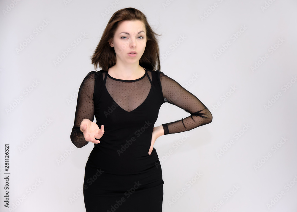 Portrait on white background of a pretty slim beautiful fashionable adult girl with beautiful brunette hair in a black dress. Standing talking demonstrating different poses and emotions Portrait on white background of a pretty slim beautiful fashionable adult girl with beautiful brunette hair in a black dress. Standing talking demonstrating different poses and emotions