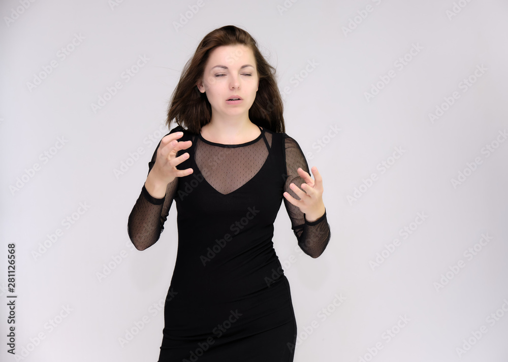 Portrait on white background of a pretty slim beautiful fashionable adult girl with beautiful brunette hair in a black dress. Standing talking demonstrating different poses and emotions Portrait on white background of a pretty slim beautiful fashionable adult girl with beautiful brunette hair in a black dress. Standing talking demonstrating different poses and emotions