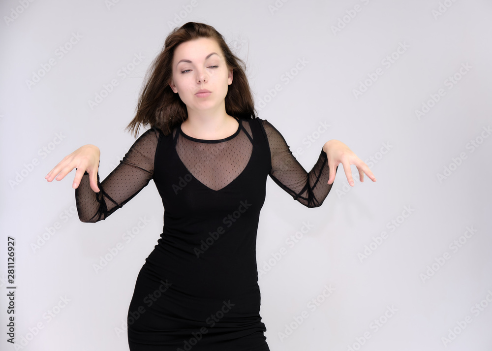 Portrait on white background of a pretty slim beautiful fashionable adult girl with beautiful brunette hair in a black dress. Standing talking demonstrating different poses and emotions Portrait on white background of a pretty slim beautiful fashionable adult girl with beautiful brunette hair in a black dress. Standing talking demonstrating different poses and emotions