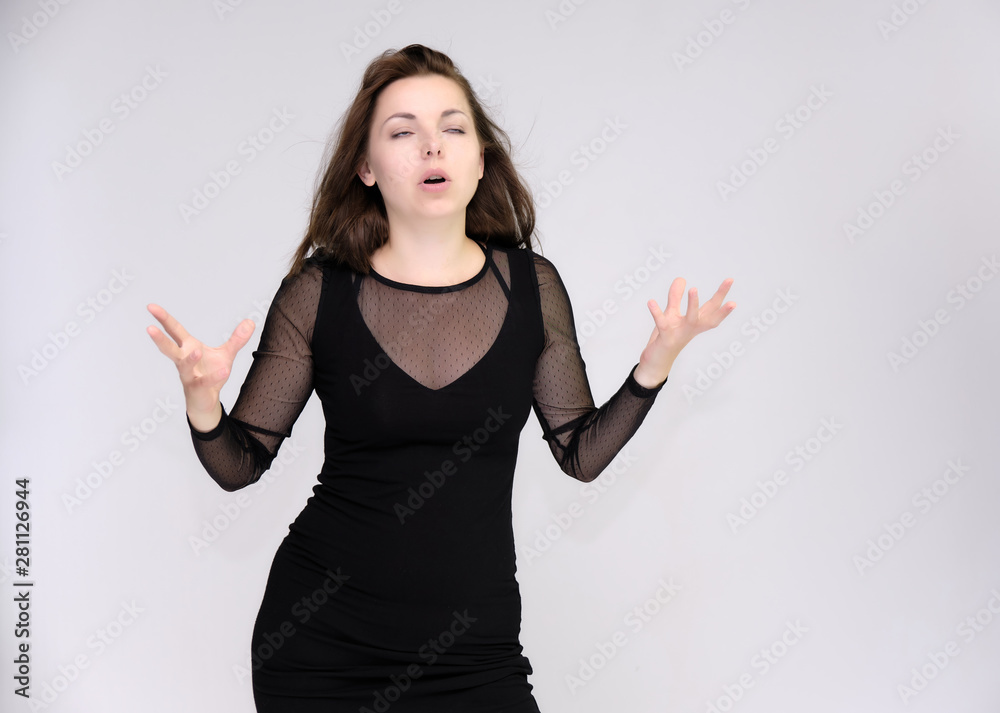 Portrait on white background of a pretty slim beautiful fashionable adult girl with beautiful brunette hair in a black dress. Standing talking demonstrating different poses and emotions Portrait on white background of a pretty slim beautiful fashionable adult girl with beautiful brunette hair in a black dress. Standing talking demonstrating different poses and emotions