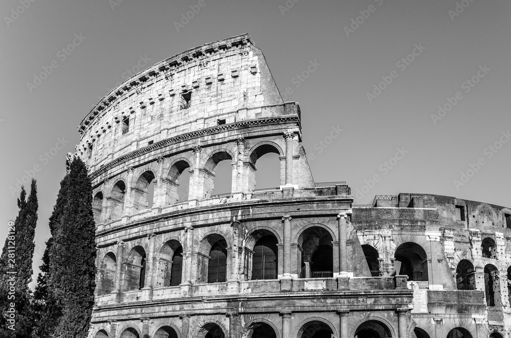 Black & white image of the ancient Colosseum, also know as Flavian Amphitheatre or Colosseo, an oval amphitheatre east of the Roman Forum with a clear sky in the historical city of Rome, Italy, Europe