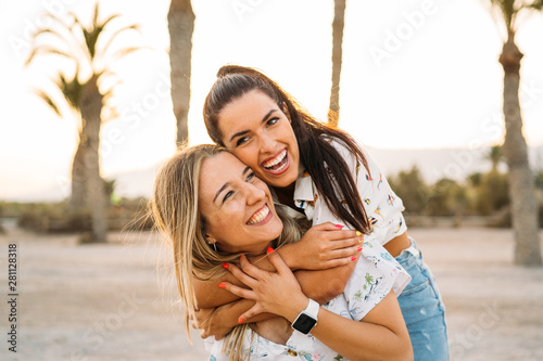 Two smiling friends hugging each other on the beach during sunset. Happy and Friendship concept.