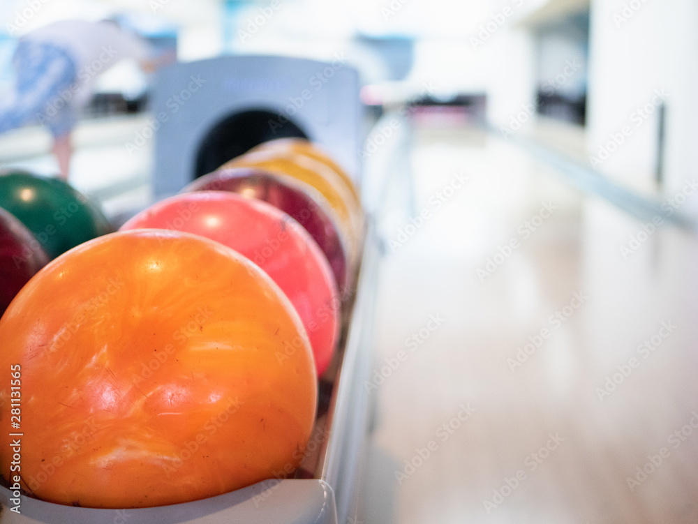 closeup of vivid orange bowling ball. selective focus on foreground with blurred track lane on background