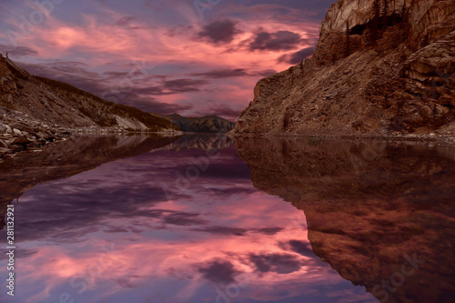 Reflection of mountain and sunset sky on calm alpine lake. Ha Ling Peak reflection in Whiteman's lake near Canmore. Kananaskis. Alberta. Canada.