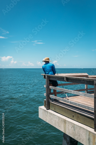 Fisher man look to the blue ocean at pier. 
