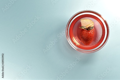 Strawberry jelly with fresh berries, a thin slice of apple and a leaf of basil. In a transparent outlet on the right on a blue background.