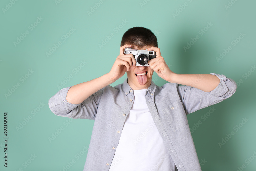 Teenage boy with photo camera on color background