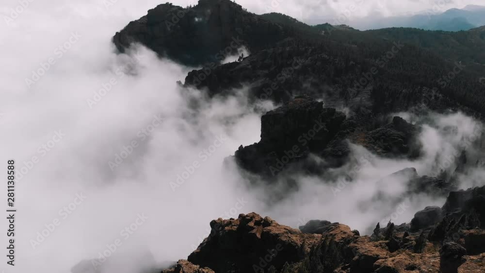 Aerial view - beautiful clouds curl in the gorges of the mountains, view from a high altitude of the valley of volcanic origin, Pico de las Nieves, Gran Canaria Aerial view - beautiful clouds curl in the gorges of the mountains, view from a high altitude of the valley of volcanic origin, Pico de las Nieves, Gran Canaria