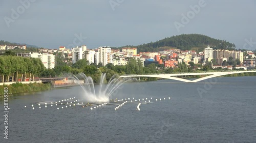 View of Mondego river with water fountain and Pedro e Ines pedestrian bridge, Coimbra, Portugal photo