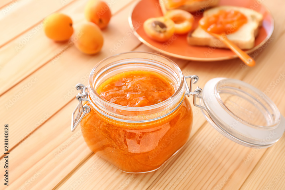 Jar of tasty apricot jam on wooden table Jar of tasty apricot jam on wooden table