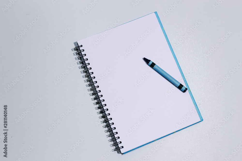 White clean notebook with blue crayon