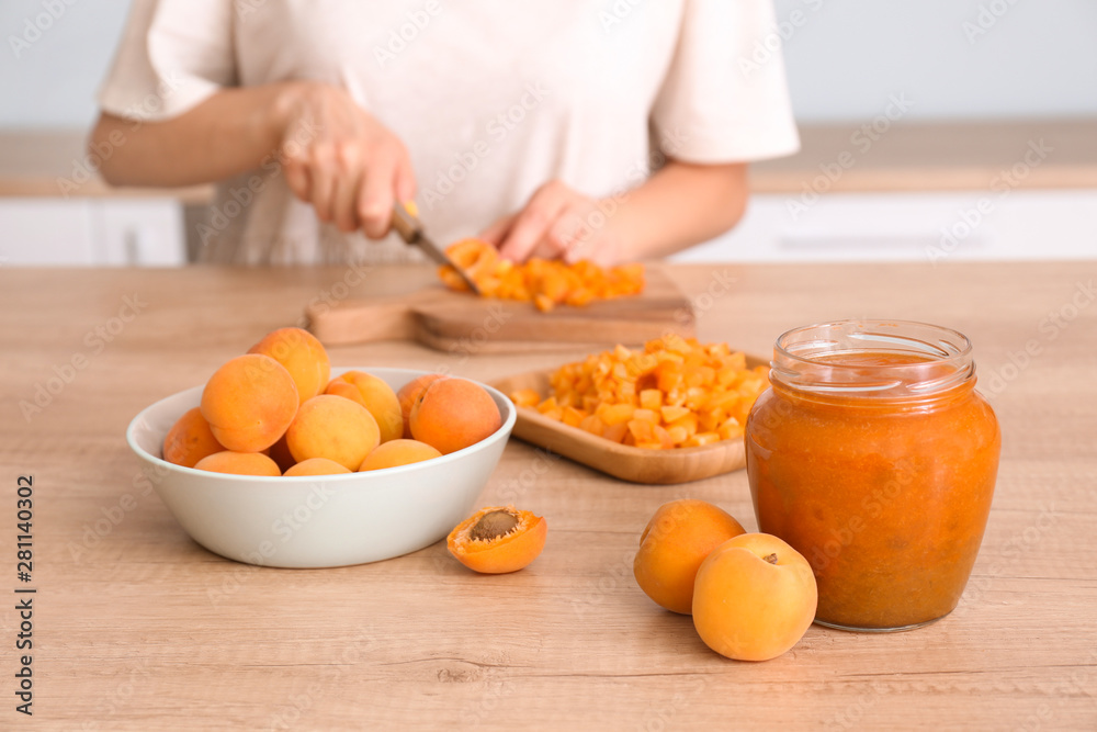 Woman preparing tasty apricot jam at table Woman preparing tasty apricot jam at table