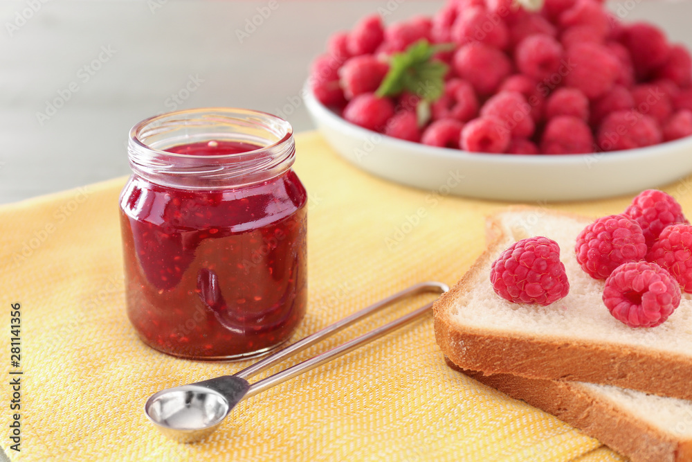 Tasty raspberry jam with fresh bread on table