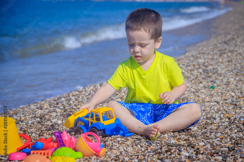 The boy plays on the beach in the toys for the sand. Children's games. Games on the beach. Galichny beach. Children's toys for sand. The baby is playing The boy plays on the beach in the toys for the sand. Children's games. Games on the beach. Galichny beach. Children's toys for sand. The baby is playing