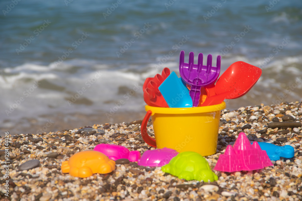 Plastic children's toys for sand on the background of the sea. Kids toys. Plastic sand toys. Bright toys. Sand construction. Children's activities. Hobbies and recreation.