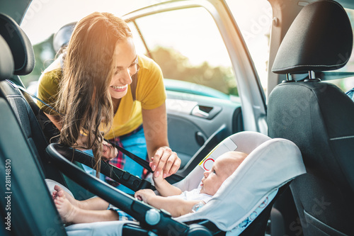 Bild auf Leinwand Young mother putting her baby boy on a safety child car seat.