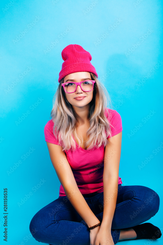 young pretty teenage modern hipster girl posing emotional happy on blue background, lifestyle people concept young pretty teenage modern hipster girl posing emotional happy on blue background, lifestyle people concept