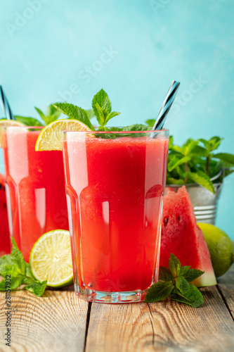 Watermelon slushie with lime and mint, summer refreshing drink in tall glasses on a light blue background. Sweet cold smoothie