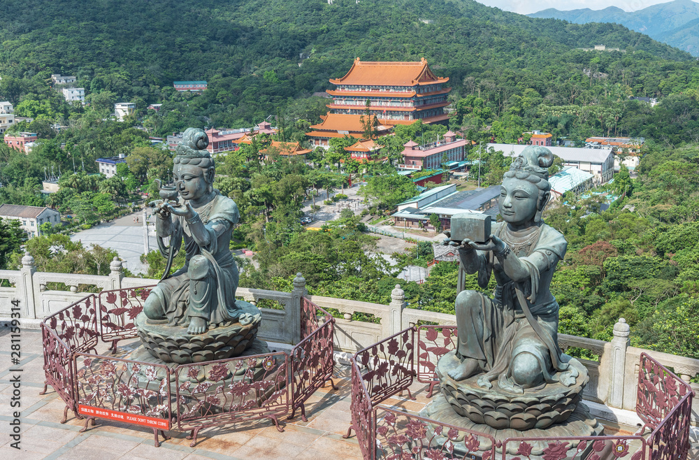 Obraz premium Buddhist statue praising and making offerings to the Tian Tan Buddha with Po Lin Monastery at background in Lantau island, Hong Kong