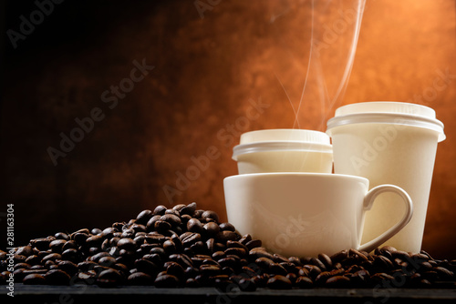 The cup and Styrofoam cup with hot coffee and coffee beans on the table