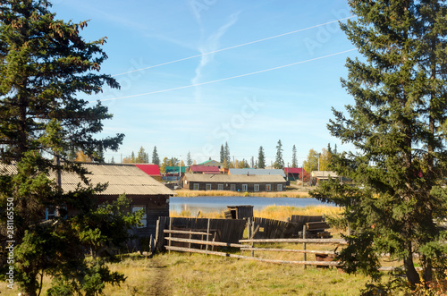 Bright day in the village of ulus Suntar in Yakutia on the overgrown pond in spruce trees with wooden barracks and toilet.