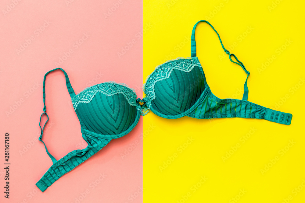 Green female bra on yellow and pink background. Flat lay. - obrazy, fototapety, plakaty 