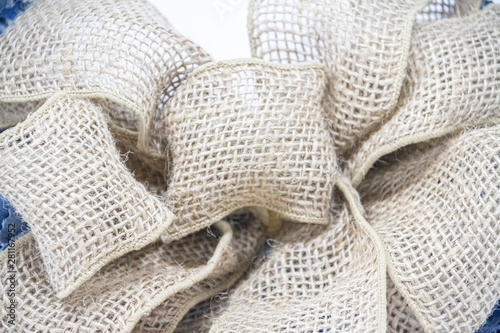 A detailed image of an elaborately tied bow made up burlap material.